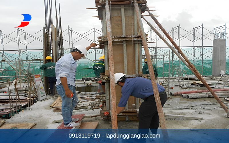 Công nhân đang lắp ráp các tấm cốp pha xây dựng bằng thép cho cột vuông của tòa nhà.